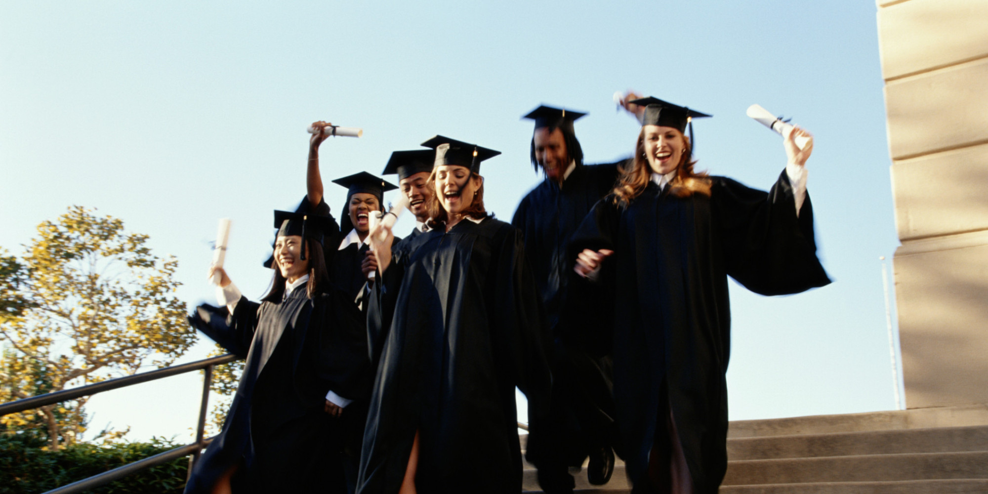 College graduates running down steps