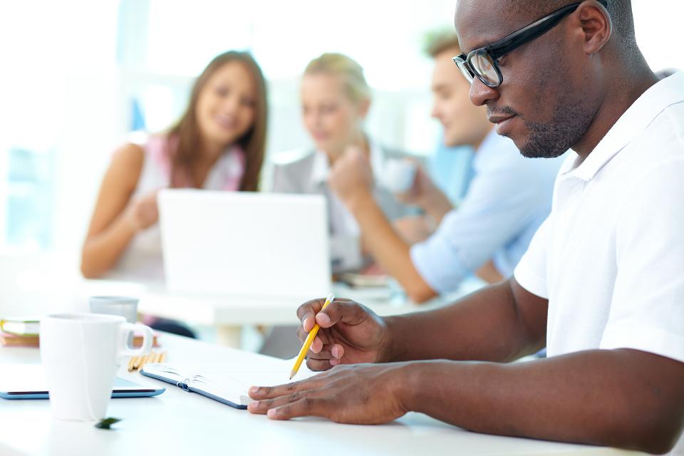 Portrait of cute African guy working with his partners on background